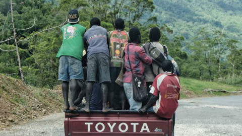 Four men standing on the back of a Toyota truck, in Bougainville